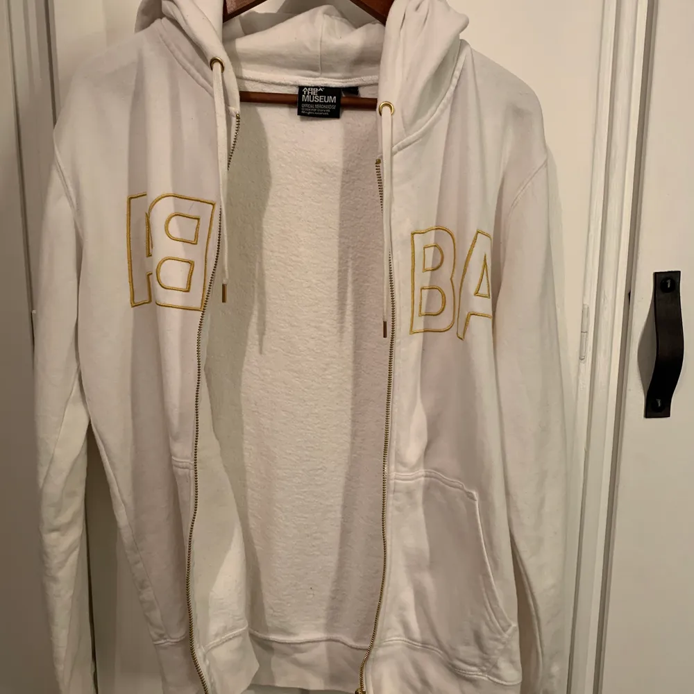 En vit zip up hoodie/ kofta med guld detaljer som är köpt från ABBA museet. Har inte haft användning av den på ett tag och den är i ett fint skick men dock med ett fåtal fläckar som enkelt kan tas bort.. Tröjor & Koftor.