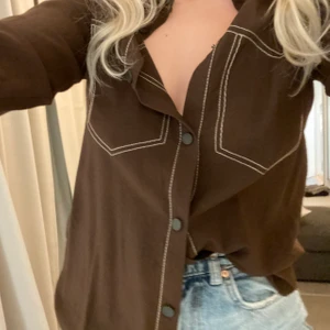 Brun skjorta med vita sömmar! - Brun skjorta med sömmar ifrån Zara! Säljer pga av för liten för mig som vanligtvis är M så skulle säga att denna är en S mer än M.  Skriv för fler bilder 🤎 köparen står för frakt!