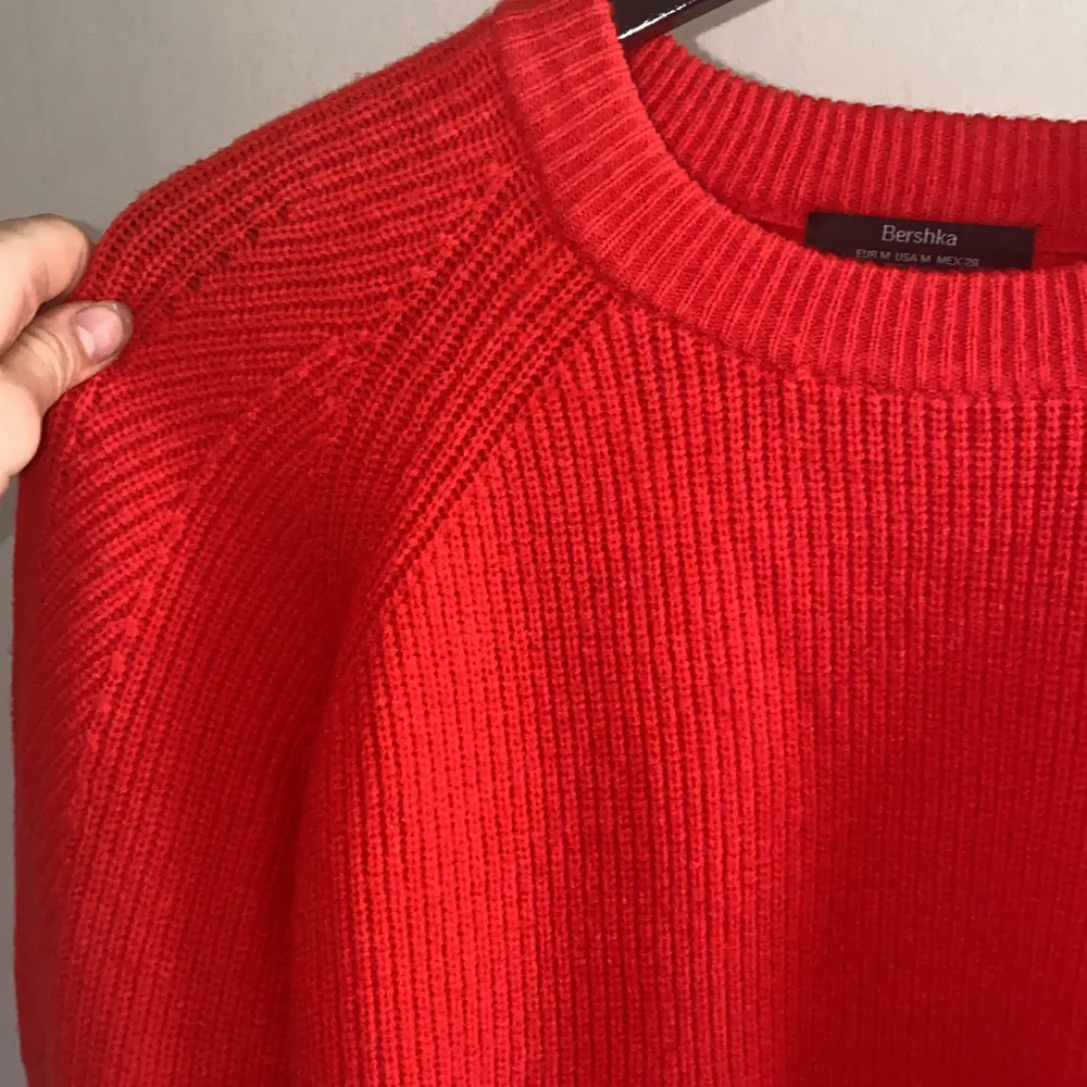 Säljer en superfin röd stickad tröja. På bilderna ser det ut som att den är mer åt ett varmt oranget håll. Men tröjan är egentligen en mer kall röd färg med lite rosa underton. Tröjan är perfekt nu till våren, eller till sena sommarkvällar!. Stickat.