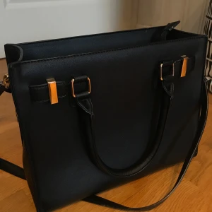 Svart damväska  - Medelstor svart damväska med guld detaljer