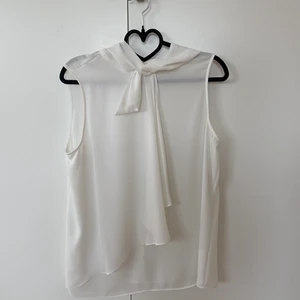 Vit blus  - Lätt vit blus med fint fall i linneform. Den knäpps med knappar i nacken, är i storlek S och kommer från Mango. Knappt använd. 