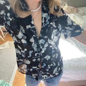 Vitage blus - Fin blå vintage blus med blommor på. Materialet är luftigt och lite genomskinligt (med avsikt). Storlek står inte men passar bra på mig som är S och säkert M också. 