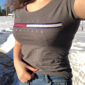 Tommy Hilfiger t-shirt grå - En grå, hyfsat tajt t-shirt från Tommy Hilfiger. Märket är rätt slitet då den är använd ett par år. 