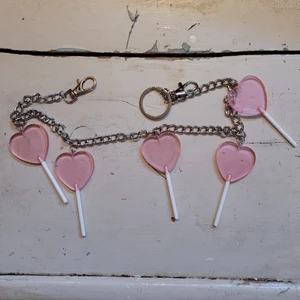 Söt kedja med klubbor - Jättesöt kedja att fästa i byxor eller bälten som pryds av flera hjärtformade rosa klubbor! 💗🍭 Jag tycker att denna är jättefin men känner inte att den passar min stil längre. Felfritt skick.