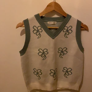 En vest - Den har blommor vänster den är blå grön och vit den är mjuk kanterna är det lite annorlunda tyg den stretchar ganska mycket bakom finns det också blommor