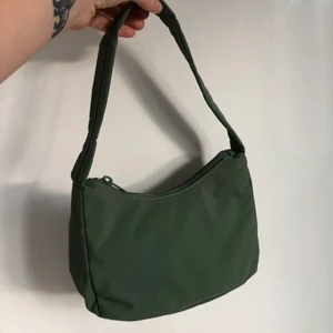 Mörkgrön handväska 90tal - Mörkgrön axelväska/handväska i 90talsmodell. Riktigt fin och i en trendig färg! Aldrig använd. Fyllningen är kvar i tillochmed. Snygg till denim. Kan bli billigare frakt om jag tar ut fyllningen och viker ihop den i Postnords blå påse S. Köpt för 249kr.
