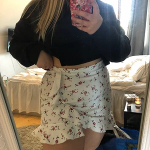 Blommig kjol  - Fin kjol med rosa blommor och gröna blad på. Kort modell, slutar innan rumpan. Aldrig använd! 