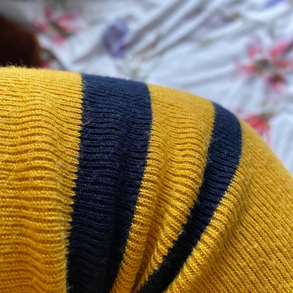 fin solros-gul tröja med två blåa ränder på magen samt armarna. den är lite croppad fast inte jätte. ränderna ser svartare ut i verkligheten. väldigt fint skick. . Stickat.