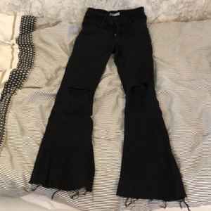 Svarta bootcutjeans med hål  - Svarta jeans med hål på knäna. Inte använda särskilt mycket då de blivit för små för mig. Det är hål på knäna. Nypris 499kr 