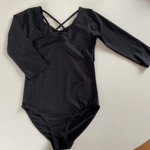 Gymnastikdräkt dansdräkt HM svart 146/152 - Nyskick! Gymnastikdräkt med trekvartsärm och kors i ryggen. Slutsåld på HM. Använd 1-2 ggr. Hämtas i Djursholm eller skickas mot porto (114 gram).