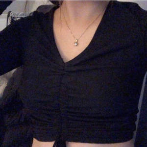 Svart topp - Svart långärmad topp med "knyte" så man kan dra åt hur lång eller kort man vill ha den