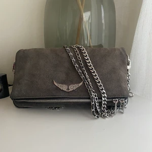 Zadig voltaire rock suede väska - Säljer min zadig väska i mörkgrå mocka då den inte kommer till användning längre, väskan kommer med tre band, två korta och ett långt. Köpt förra sommaren för ca 3200kr men säljer för 1600kr. Tar även bud