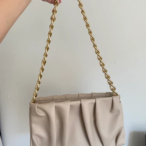 Mq - Beige axelväska med gulddetaljer och dragkedja. Använd en gång, nyskick! Skickas med spårbart frakt eller annat alternativ som vi kommer överens om.