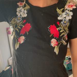Svart t-shirt med blommor och stenar 