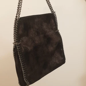 Svart handväska - Svart glittrig handväska med en jätte snygg kedja. Helt oanvänd eftersom jag aldrig hade någonting att para ihop den med. Snygg mönster på insidan. Lik Stella McCartney väskan. Köpt från myrorna. Jätte bra skick