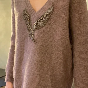 Stickad tröja med detalj - En gosig stickad tröja med strassdetalj, i en dov ljuslila färg. V-ringad. Använd 1 gång. Nypris: 549