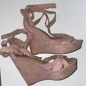 Rosa kilklackar med snörning - Säljer ljusrosa kilklackar i mockaimitation med snörning i storlek 37. Klacken mäter 11cm MEN med platå på 4cm, enkla att gå i.