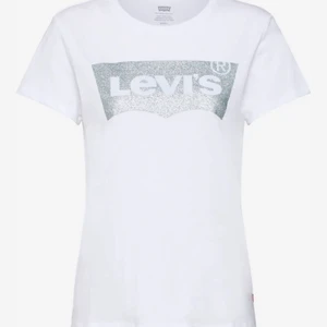 Levi’s T-shirt - Vit Levis tröja med Levis märket omringat av silver. Är i storlek S! Använd fåtal gånger så är fortfarande i mkt bra skick!  Köparen står för frakten på 48 kr!