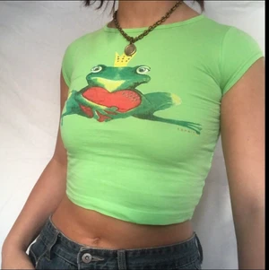Grodprins grön babytee  - Sötaste babytee med en groda på. Smyckad med rhinestones! Gott defetfritt skick. Köpare står för 24kr frakt. Barnstorlek men uppskattas passa xs. Visas på en s 