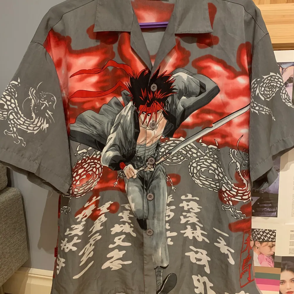 Tshirt ärmad skjorta med manga/anime tryck. Har ett hål på höger sida som visat på bilden, och några lösa trådar. Jag tkr knappt att hålet märks me skjortan på men de går nog lätt att sy ihop. . Skjortor.