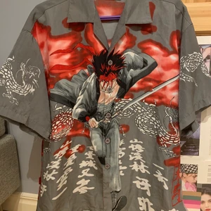 Graphic Manga T Shirtsleeved Shirt  - Tshirt ärmad skjorta med manga/anime tryck. Har ett hål på höger sida som visat på bilden, och några lösa trådar. Jag tkr knappt att hålet märks me skjortan på men de går nog lätt att sy ihop. 