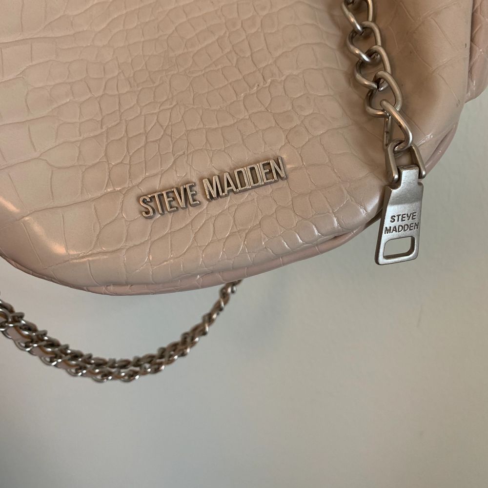 En jätteälskad beige väska från Steve Madden som jag har använt mycket men som ändå är i väldigt bra skick! Köpte den för cirka 900-1000kr och säljer den för 299kr + frakt 💕 Den har ett tjockare band och ett jättecoolt kedjeband. Alla detaljer är i silver och materialet är ett glansigt krokodilliknande mönster 🤩🐊🖤 Öppen för prisförslag!! 💓💞. Väskor.