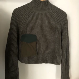 Militärgrön tröja - Kort stickad tröja med hög krage från Zara. Aldrig använd. Militärgrön till färgen. Möts i Sthlm eller skickad. Köparen står för frakt.