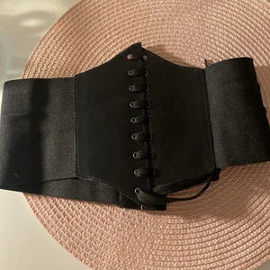 SVART KORSET 💗 - Säljer nu denna fina korsetten ifrån SHEIN! Säljes då jag råkade köpa 2 st! Den är enkel och smidig att använda med dess justerbara snören & ”skärp”. Med skärp menar jag den del som syns på foto 2! Man kan alltså sätta den runt midjan och justera baserat på hur tight man vill att den ska sitta! Den har fina snöre detaljer längst fram och sitter jättefint! 