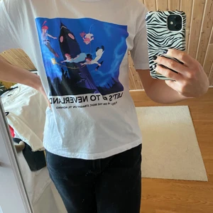 Vit T-shirt  - T-shirt med Peter Pan tryck i oversize modell. Använd men i fint skick. Hör av er för fler bilder!
