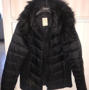 Dunjacka med fuskpäls - Svart dunjacka med fuskpäls storlek 40, skulle säga mer en storlek 38.