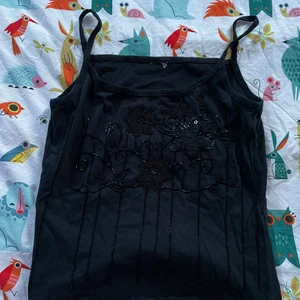 Svart linne med detaljer - Säljer ett svart linne med pärlor på jättefin att ha när man går ut eller på fest