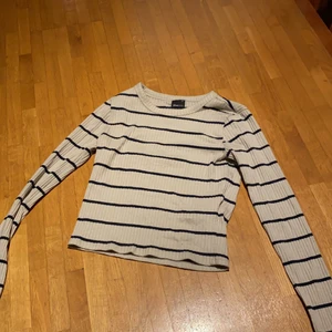 Topp - En randig topp med rippad material, tight och visar lite magen och den är från Gina tricot i stl xs