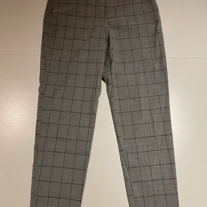 Grå kostymbyxor, 38  - Det är ett par tajta kostymbyxor i storlek 38. De är ljusgrå och rutiga och är lite kortare i benen. 