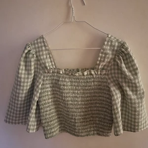Nakd ljusgrön och vitrutig topp, 36  - Detta är en ljusgrön och vitrutig topp från nakd i storleken 36. Den är sann till storleken. Modellen är lite kortare, som en magtröja och armarna puffiga. 