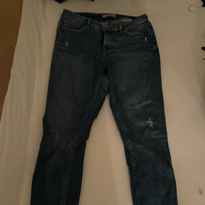 Blå slitna jeans  - Dessa jeans är superbekväma och stretchiga, storlek 42 (Medium). Dom är väldigt fina och kan matchas med massa olika plagg. Dock har dom gått sönder lite i sidan vid jeansen men det går lätt att sy ihop.  