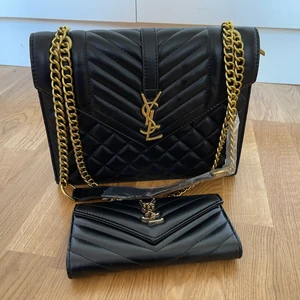 YSL bag med plånbok  - Säljer en YSL bag med matchande plånbok guldfärgade detaljer. Ej äkta! Hämtas i Lessebo eller fraktas mot fraktkostnad spårbar 99kr extra. Filmar alltid när jag postar, eller skickar med spårbar frakt. Skriver alltid avs! Jag garanterar en snabb och pålitlig affär! 🎀