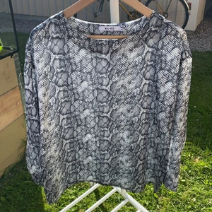 Blus från NAKD strl 34 - Fin mönstrad blus från NAKD i storlek 34 som har ett satinliknande stumt material. Blusen är i mycket fint skick och är helt oanvänd! Samfraktar gärna med andra plagg och betalning sker via Swish 🖤
