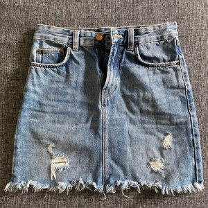 Jeanskjol - En jeanskjol. Snygga slitningar fram. 