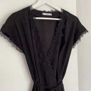 Svart miniklänning från Mango - Svart omlottklänning från mango suit som aldrig har använts. Superfin spets i uringning och ärmslut 