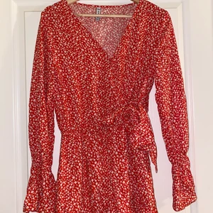 Röd sommar klänning - Säljer min röda blommönstrade klänning från New yorker i storlek S då jag inte använder den längre. Köpt förra sommarn och använd ett fåtal gånger. Den har en fin knytning i sidan och en knapp på framsidan som hindrar tyget från att glida ner. Nederdelen är även ett par shorts på insidan. Säljer för 50kr. OBS! Köparen betalar för frakten☺️