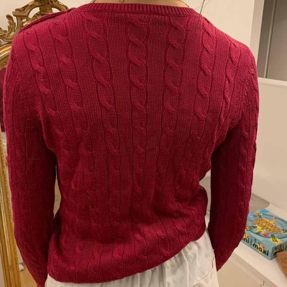 Otroligt fin och elegant tröja från Ralph Lauren♥️ Garnet är aningen blankt med en vinröd/mörkrosa nyans. På ena axeln sitter mässingfärgade knappar. Tröjan är endast använd 2-3 gånger och är i nyskick🥰. Stickat.