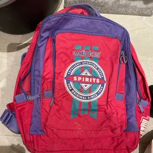 Adidas retro vintage ryggsäck 90-tal  - En Adidas ryggsäck i klassiska färger från 90-talet, många olika fickor, använt skick. Både handtag upptil och  remmar bak.