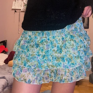 Kort kjol - Jättesöt blå/grön blommig kjol, den är insydd på sidorna. Dock är det resår i midjan! Så passar i princip alla men skulle säga storlek S.