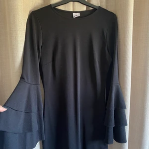 Svart klänning - Svart klänning med volang längst ut på ärmarna, från Gina i storlek 36. Använd 1 gång