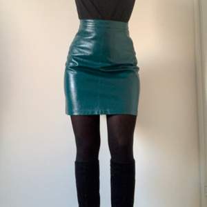 Faux leather A-line skirt in a beautiful petrol green colour (on the pictures the skirt appears more blue than in real life). There is a zipper in the back. The skirt is highwaisted and fits to mid-thighs. It is fitted on me, but can also be less fitted on someone of a smaller size than me. The skirt has never been worn before so it is in perfect condition. 