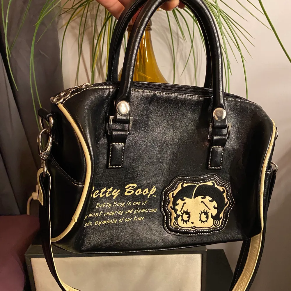 Skit snygg väska med tryck av den legendariska Betty Boop figuren. Väskan är i mycket bra skick och har ett avtagbart axelband. Köpt här från Plick och säljer då den inte kommer till så mycket användning😢. Väskor.