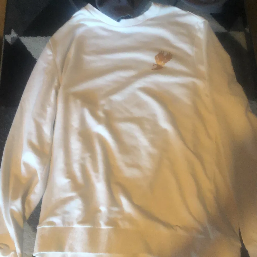 Säljer en vit sweatshirt med en guldig fågel. Säljer för att jag vill köpa en Nike tech tracksuit 🤍. Övrigt.