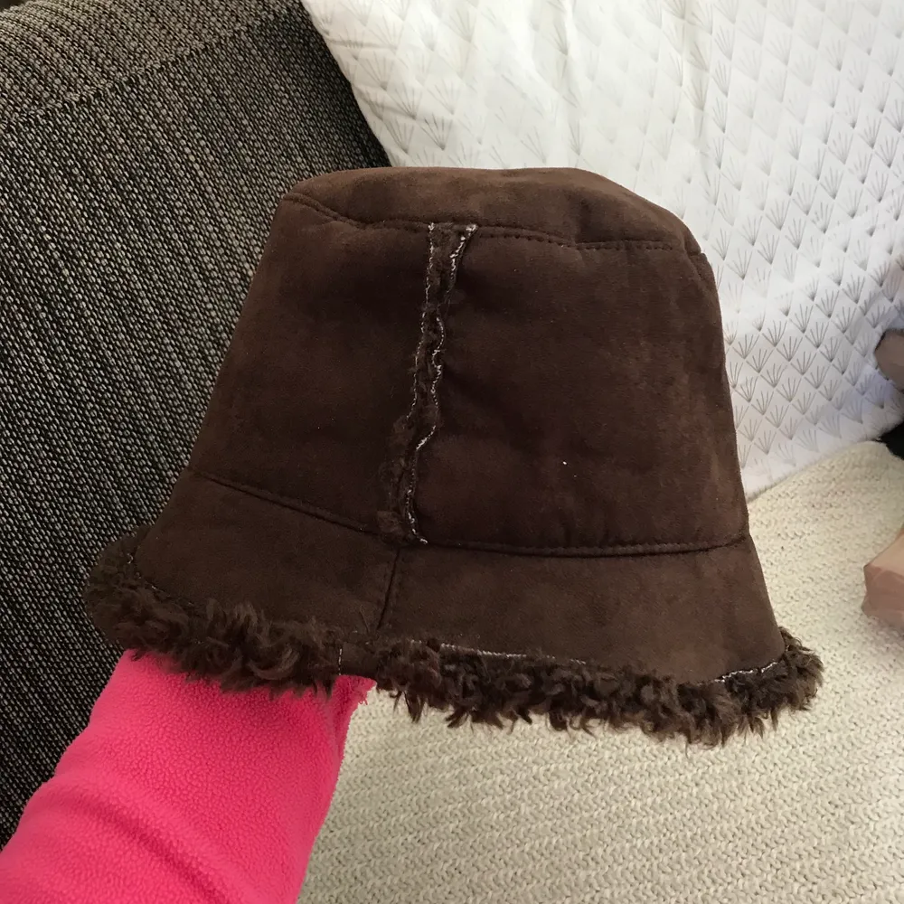 En typisk Y2K bucket hat i brun mocka och päls inuti (fake päls såklart!) 🧡✨ Skitcool, storlek M typ och snygg på både vintern o sommaren! Superfint skick, köpt secondhand men aldrig använd av mig 💕. Accessoarer.