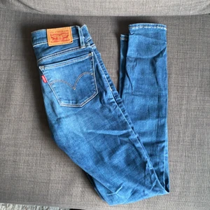 Blåa stretchiga Levis  - Blåa Levisjeans med extremt skön passform! Jag älskar dessa byxor men dem har tyvärr blivit för små. Strl 23 och även uppsydda och insydda i benen. Väldigt tajt passform men känns som ett par tights pga strechen. Mycket fint skick. Och passar någon som är max 160 lång. Kan även passa en ung vuxen/tonåring. Modell: 710 super skinny. Säljes billig pga den lilla passformen! 