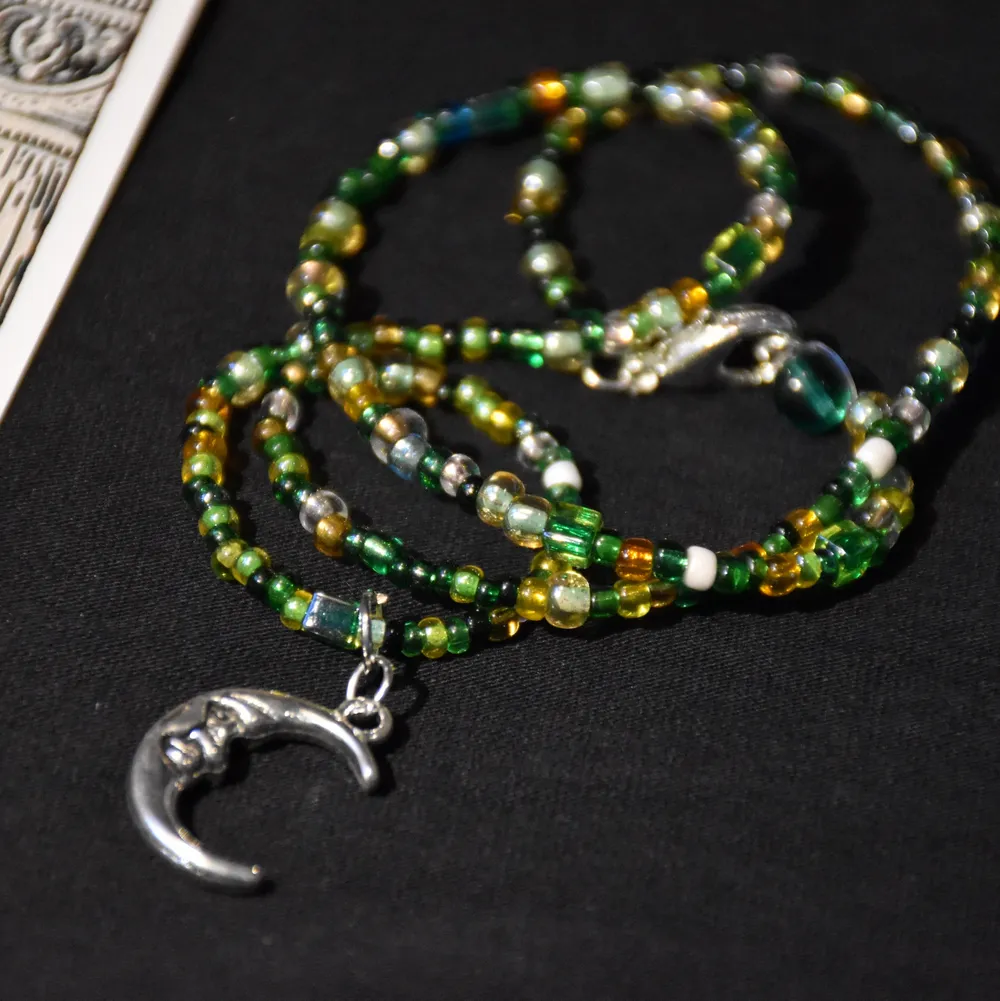 Ett enkelt halsband med gröna glaspärlor och en silvrig månberlock. Det finns endast ett! . Accessoarer.